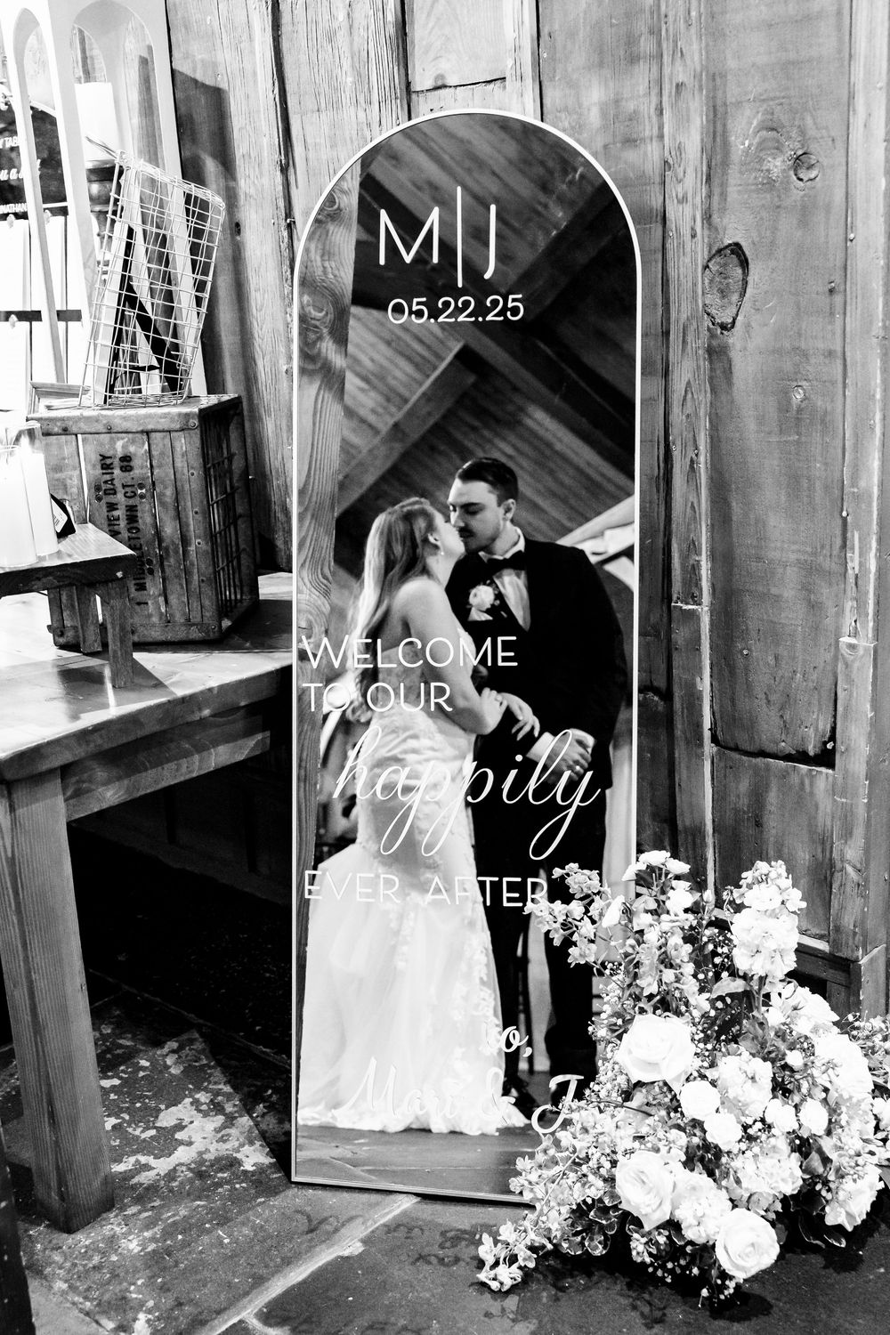 Black and white wedding photos displayed in a rustic barn setting with floral arrangements.