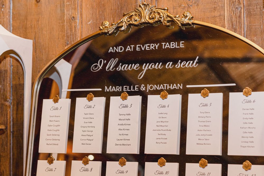Elegant wedding seating chart display with gold frame showing table assignments for guests.