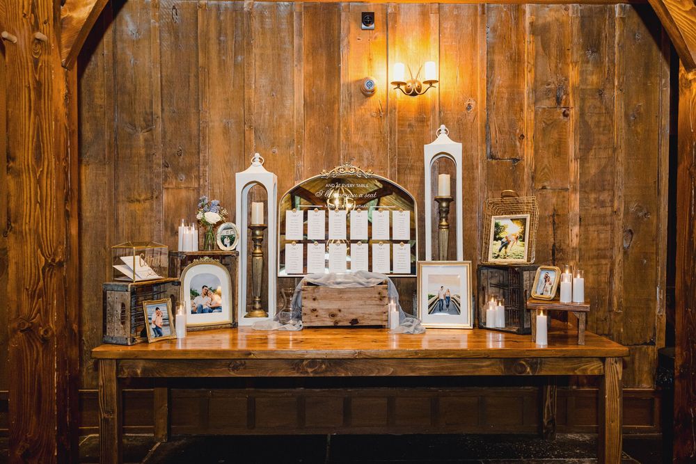 Interior view of a rustic wooden barn wedding venue decorated with warm lighting and white lanterns.
