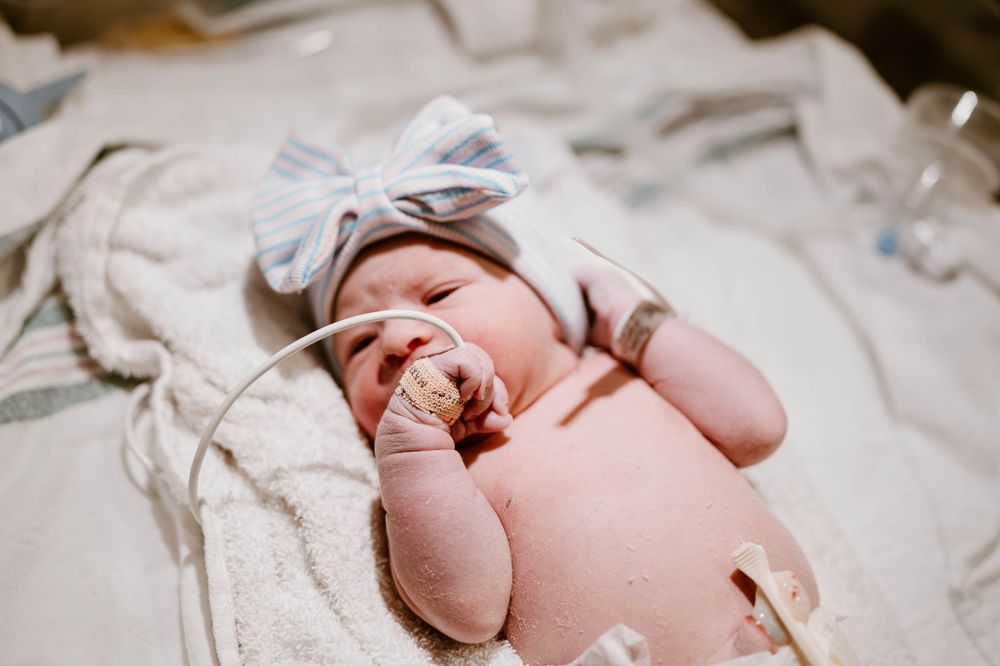 Newborn baby's tiny feet wrapped in soft white hospital blankets during first moments after birth.