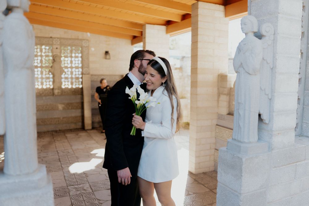 Wedding couple embracing in an elegant stone archway with wooden ceiling details.