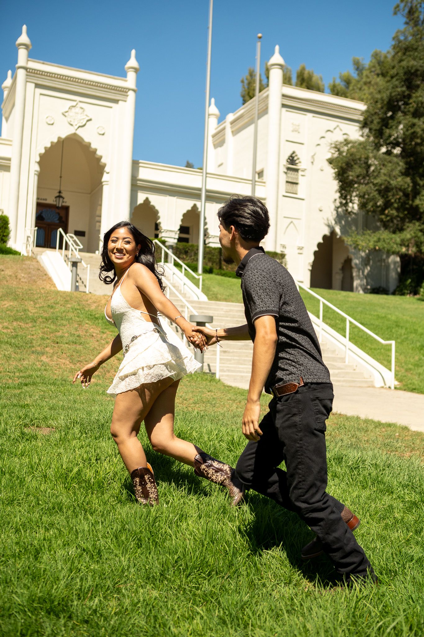 A sequence of playful tumbling action shots on a grassy hill in front of a white building.