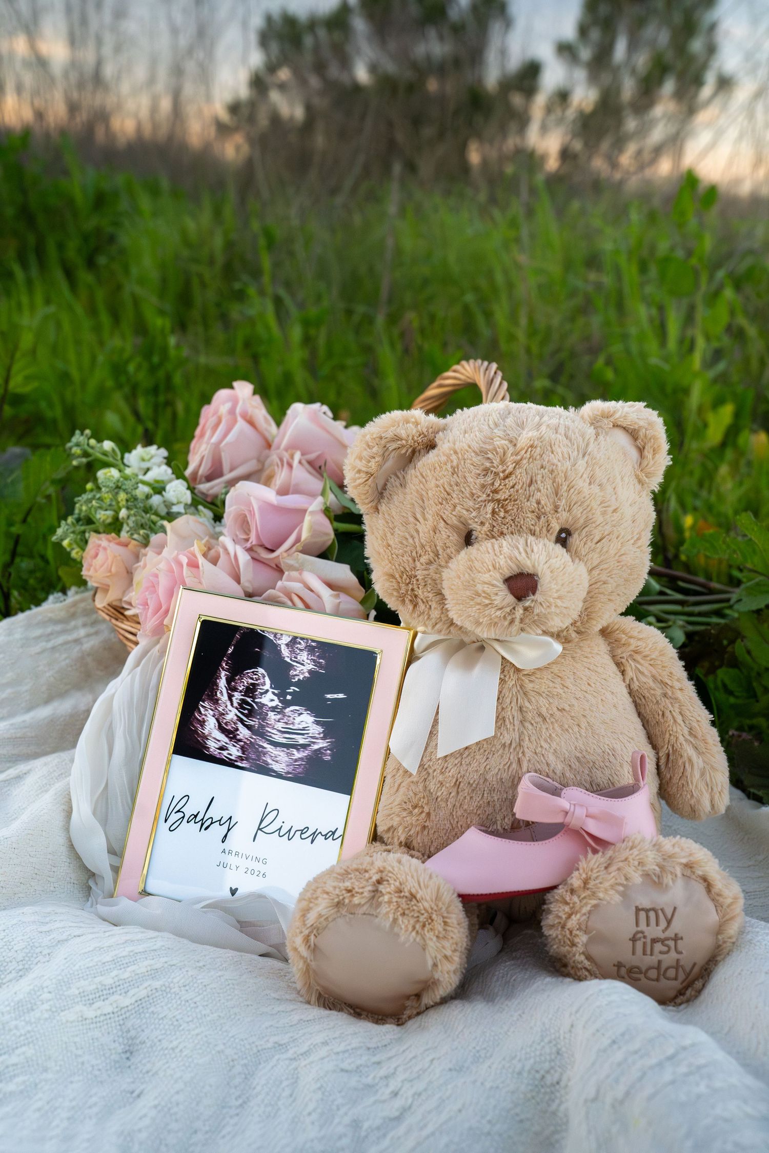 Baby announcement setup with teddy bears and ultrasound photos displayed on white fabric with pink accents.