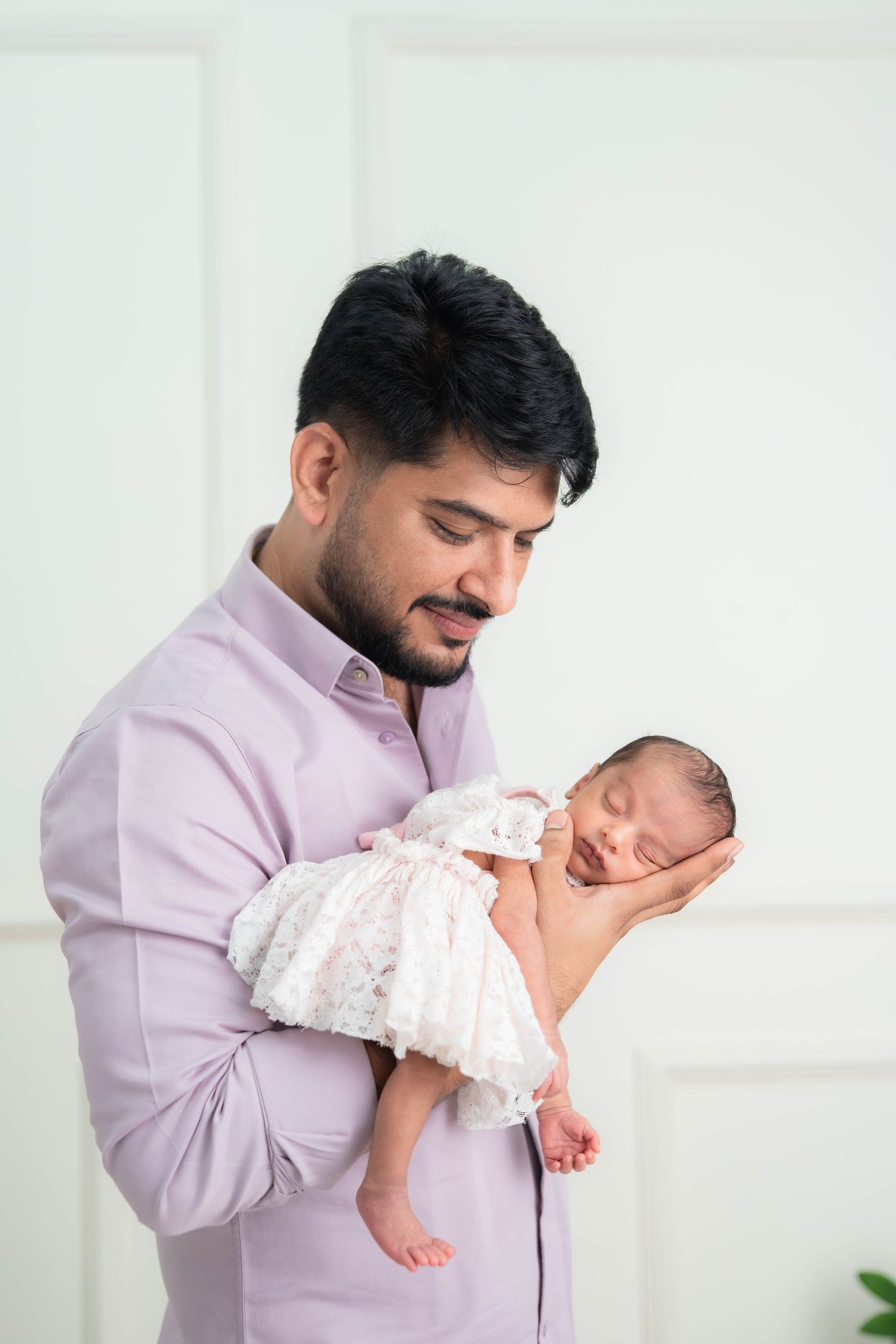 Father cradling sleeping newborn baby girl in a white lace dress - best newborn photographer in Hyderabad, Bump To Baby by Sai Jyothi
