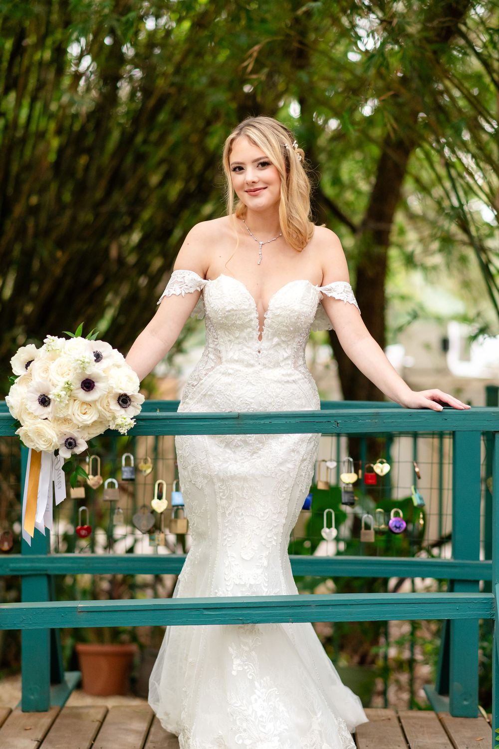 An elegant wedding portrait on a green wooden deck showcasing a fitted mermaid style dress and white floral bouquet.