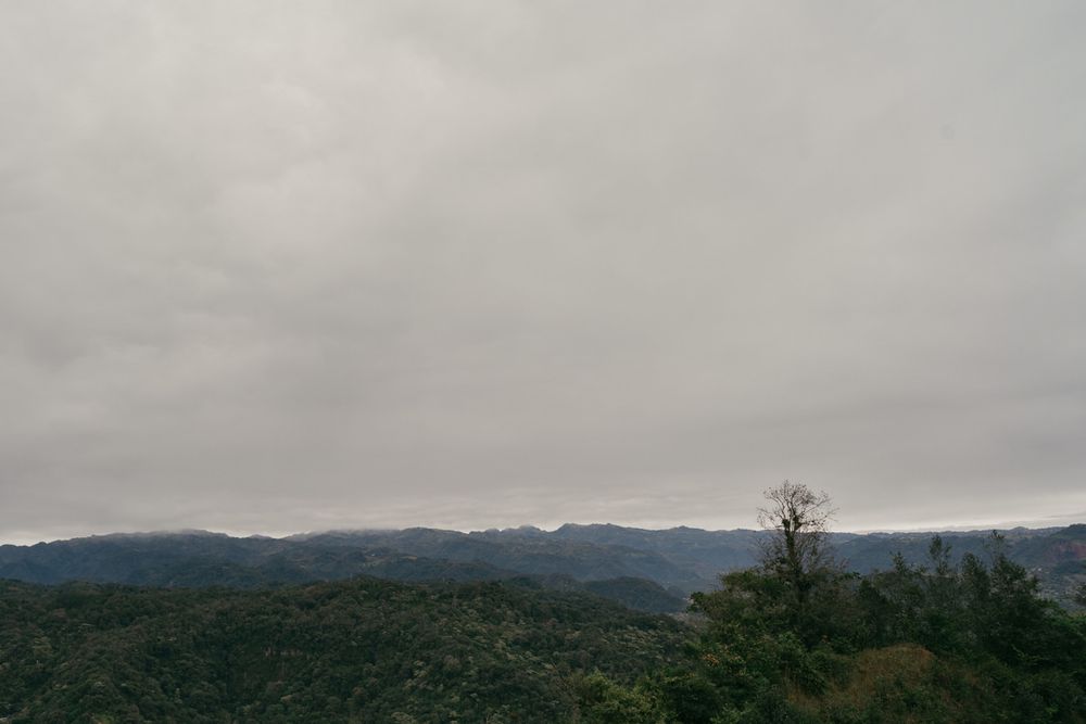 Panoramic view of misty mountains and rolling hills under a cloudy gray sky stretching across the horizon.