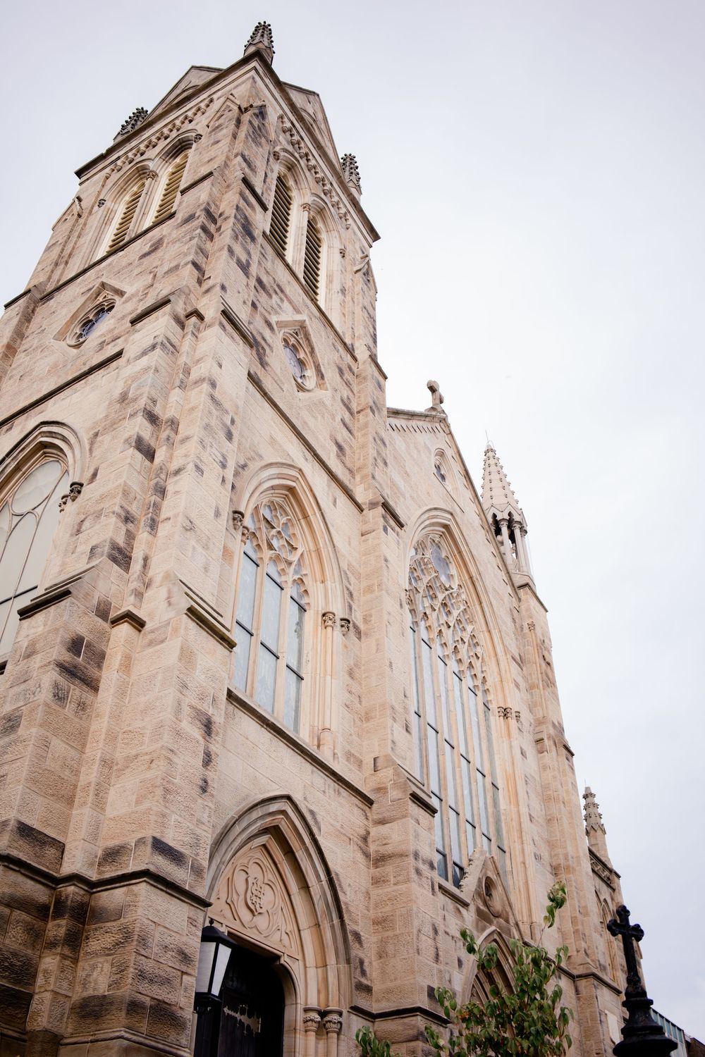 Gothic stone church exterior with ornate architectural details and tall spires against cloudy sky.
