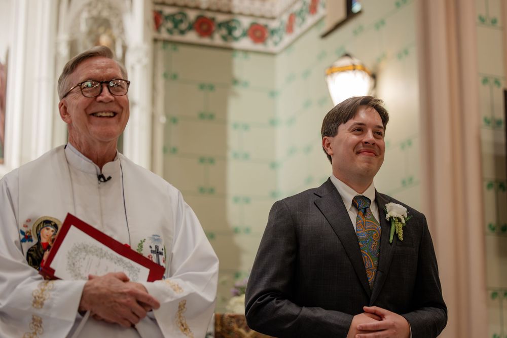 Clergy members in white robes and formal attire gather during a church ceremony.