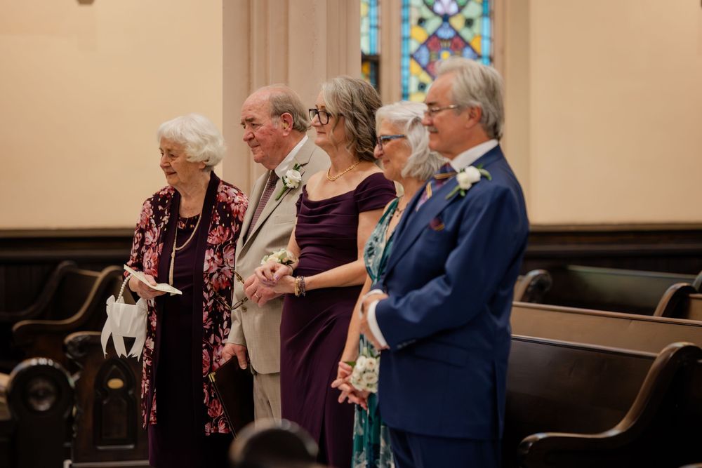 Emotional wedding ceremony guests wiping tears during service in church pews.