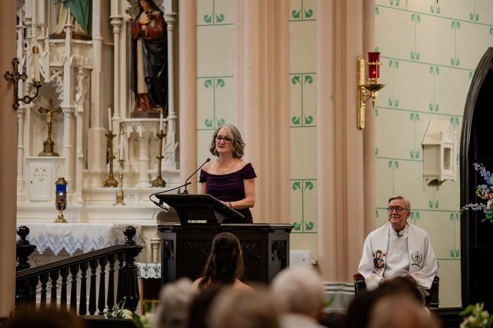Wedding ceremony taking place in an ornate church with elegant white and green decor and guests seated in pews.