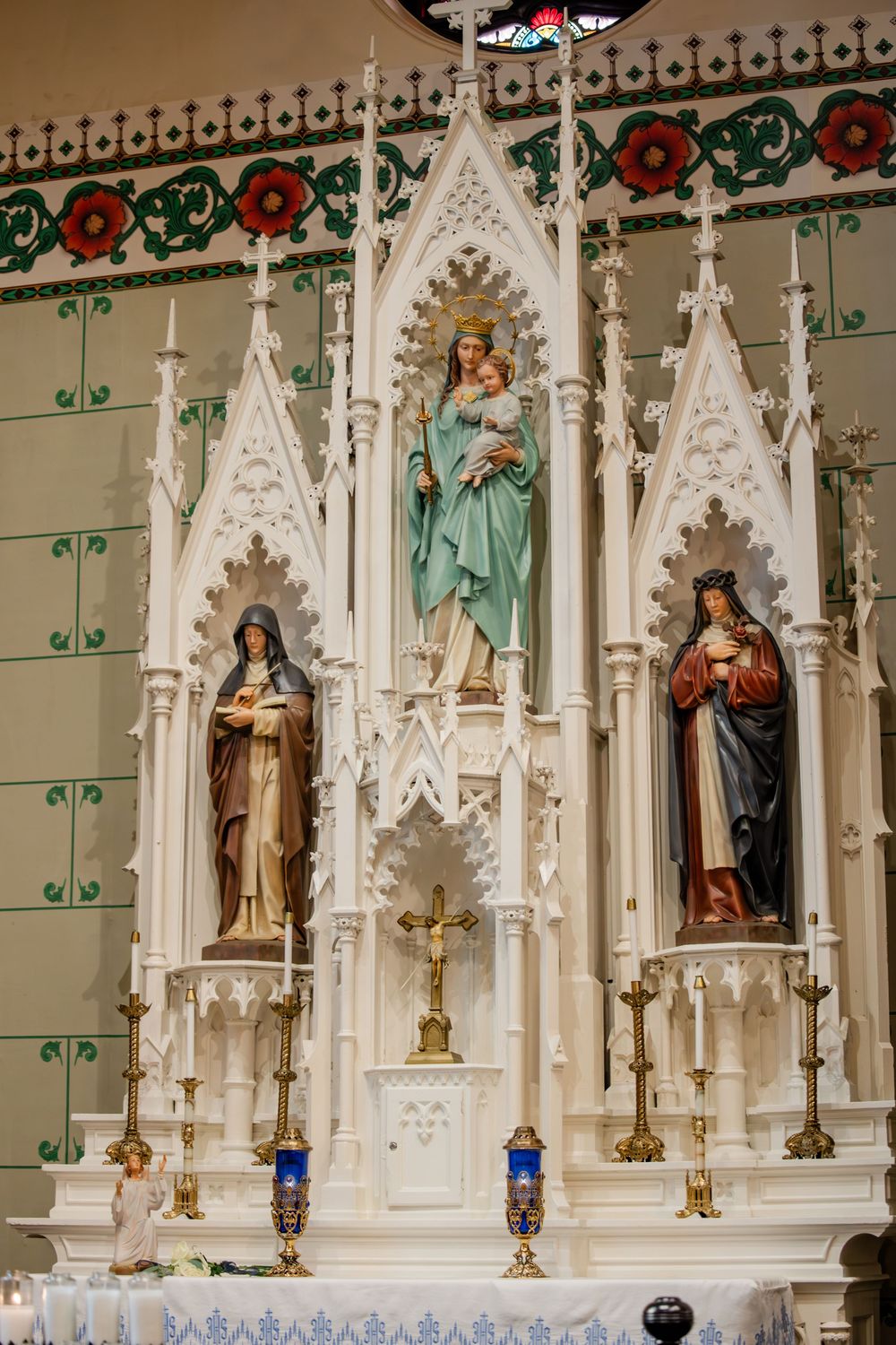 Ornate church altar featuring Gothic-style niches with religious statues and decorative floral patterns.