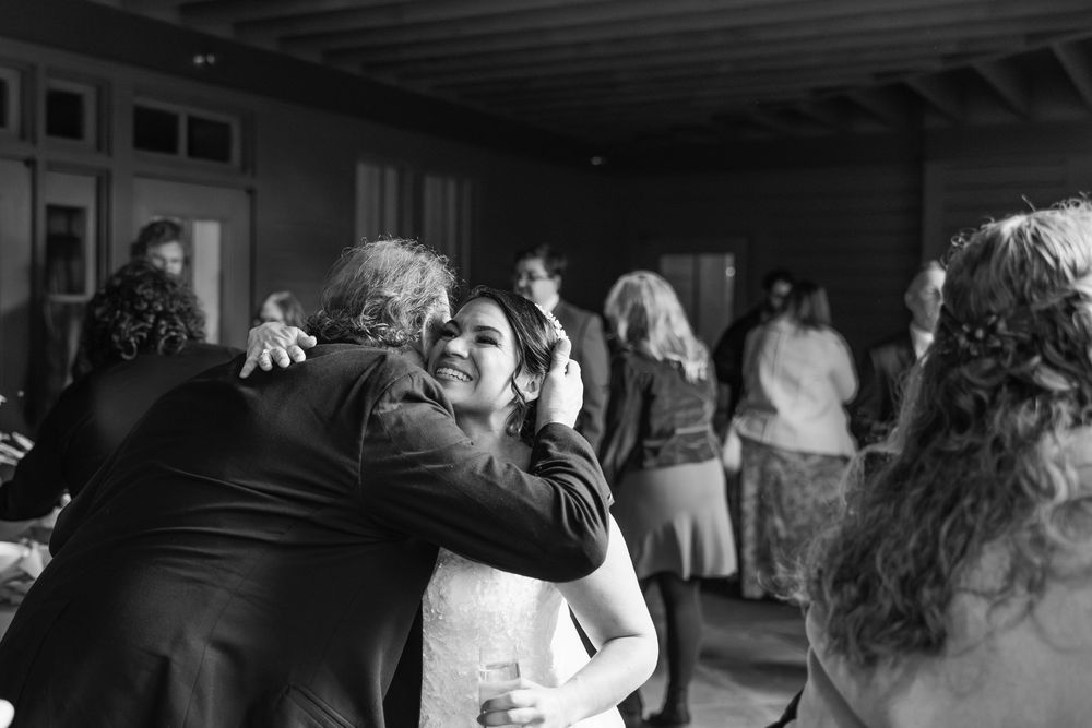 A black and white candid photograph of people dancing and socializing at an indoor event.