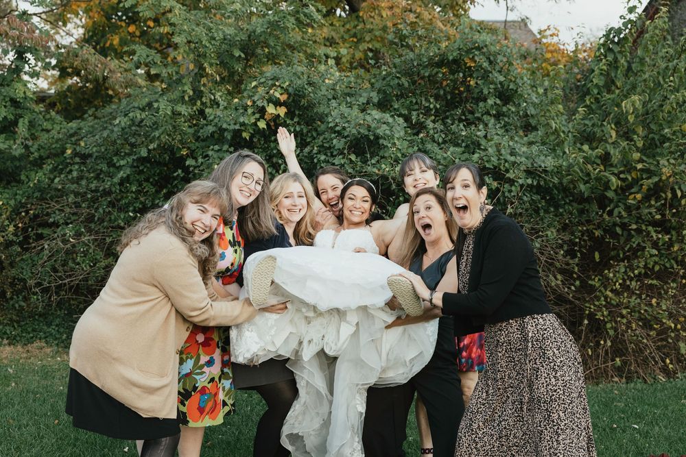A group of friends having fun and laughing together outdoors in a garden setting during autumn.