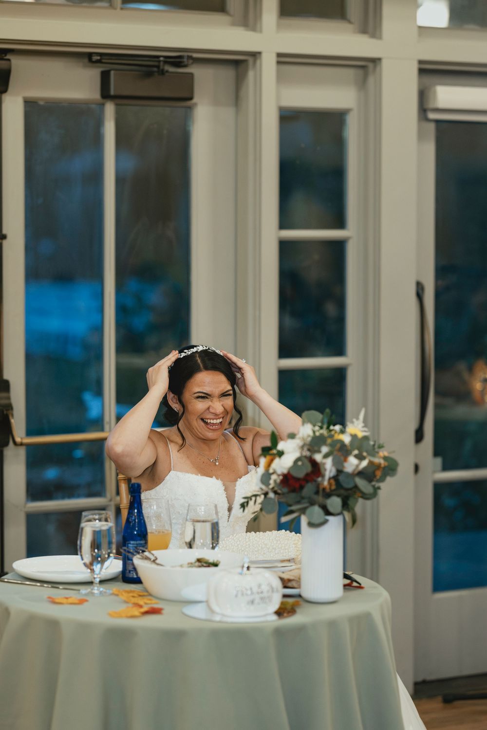 A joyful moment at an elegant wedding reception with white floral centerpieces and French doors.