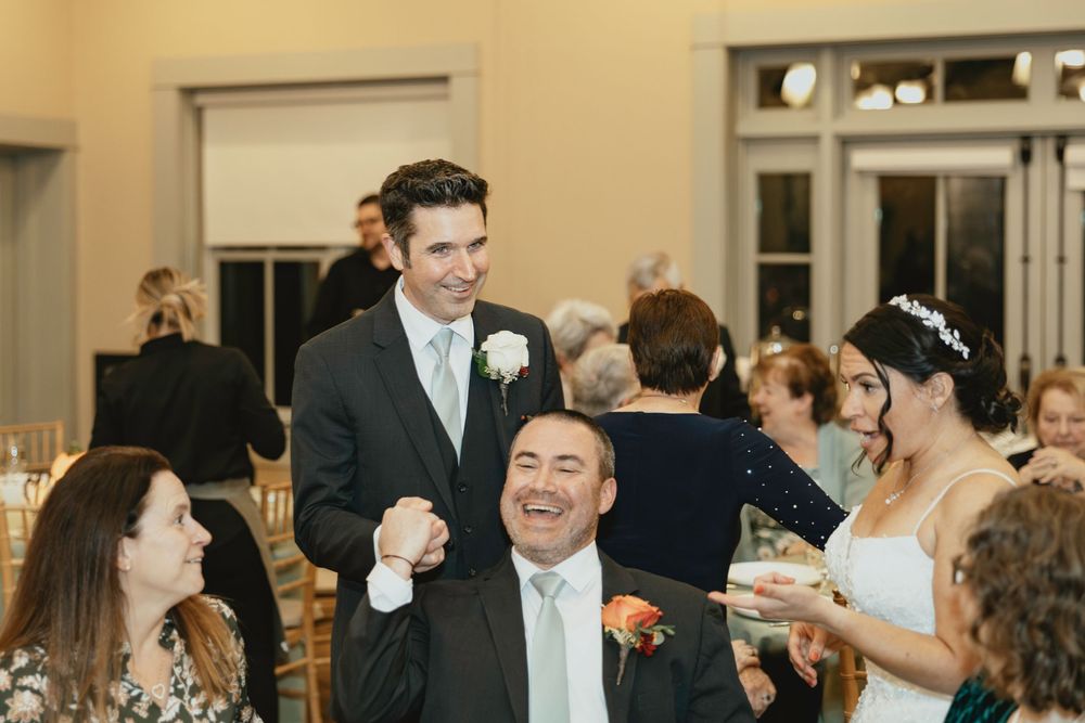 Guests enjoying a lively celebration at an indoor wedding reception with warm lighting.
