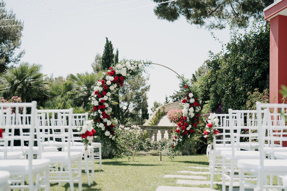 Allestimento cerimonia civile nel giardino di Villa Casa Rossa a Imperia con arco floreale rosso e bianco vista mare