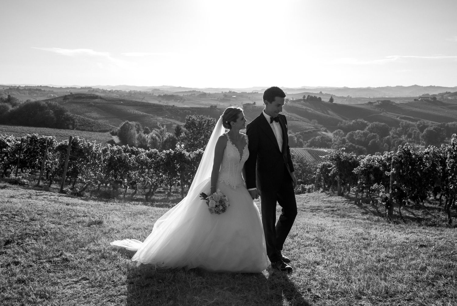 Bride and groom walking through vineyard at La Villa Hotel wedding in Mombaruzzo, Piedmont, Italy