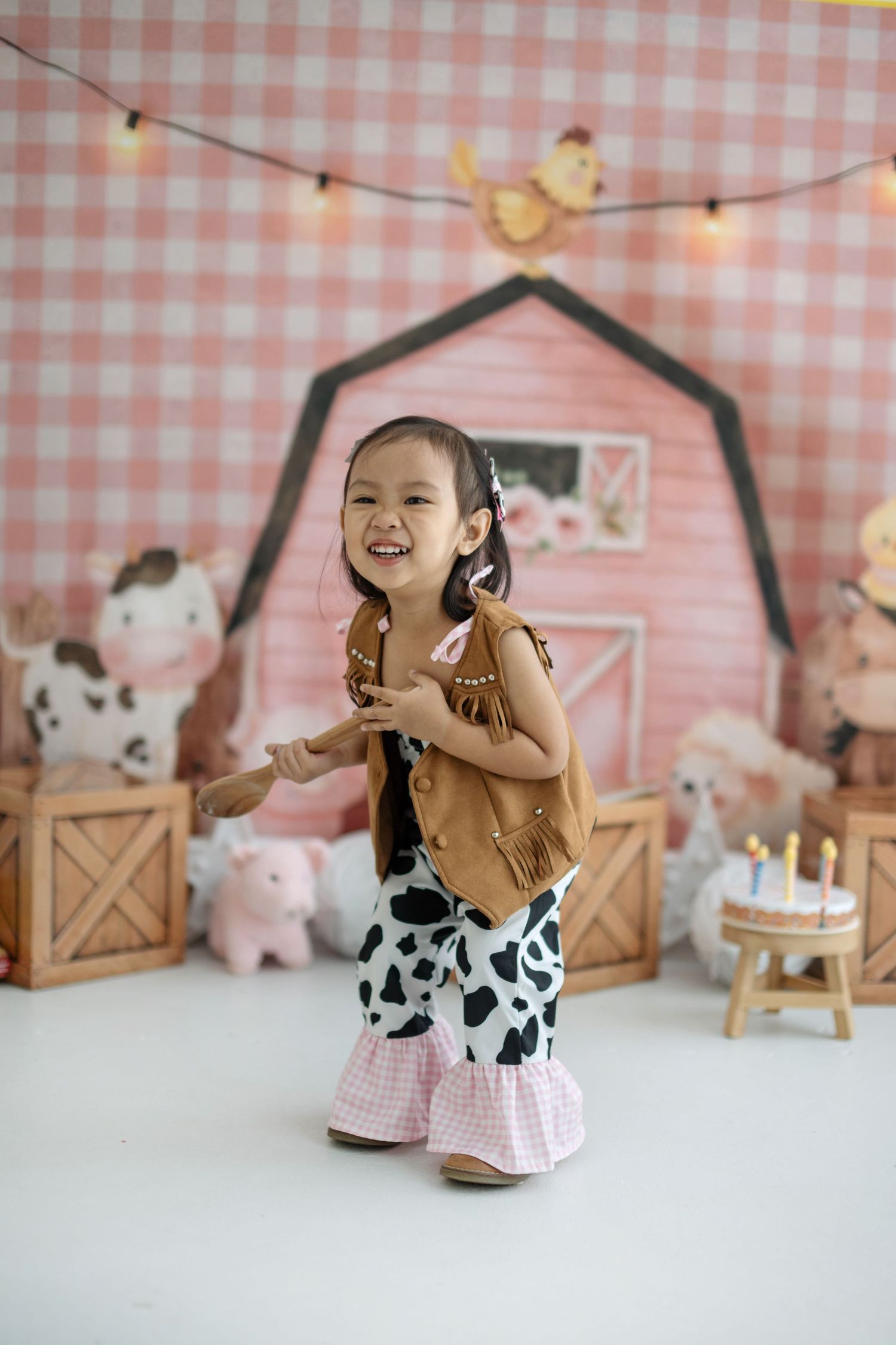 A charming birthday scene with gingham patterns, stuffed animals, and rustic barn-style decor.