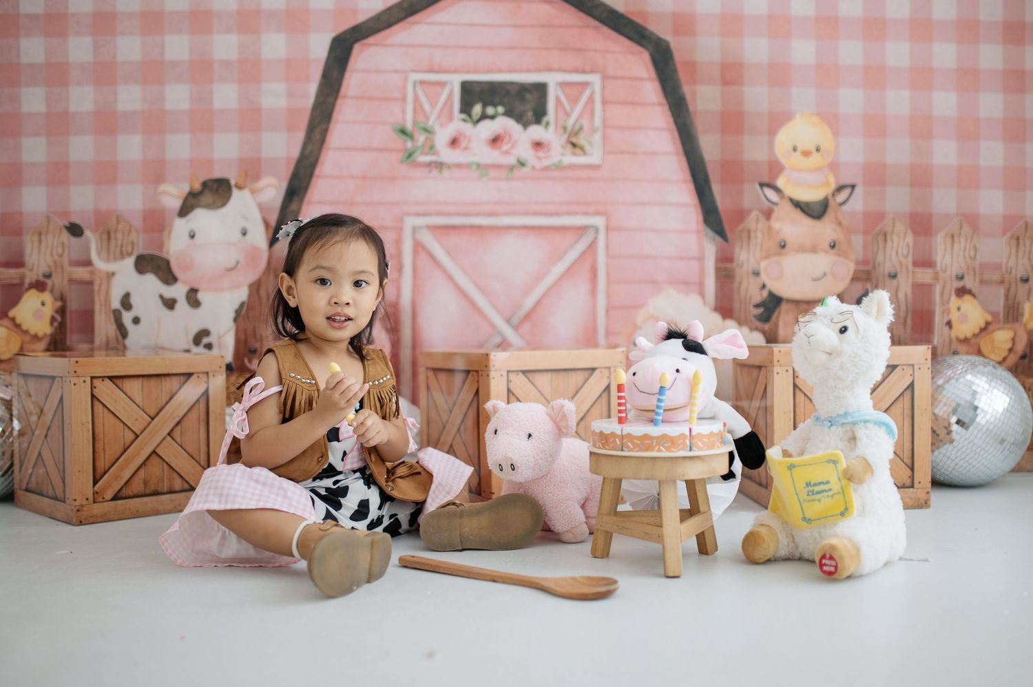 Pink gingham wallpaper and white wooden furniture create a charming nursery setting with plush toys and decor.