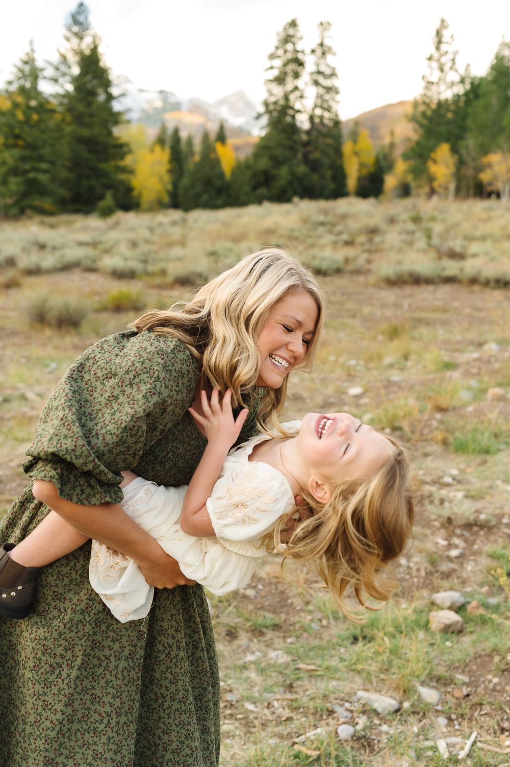 Mom and daughter share a joyful moment together while playing in a mountain field surrounded by evergreen trees at Tibble Fork.