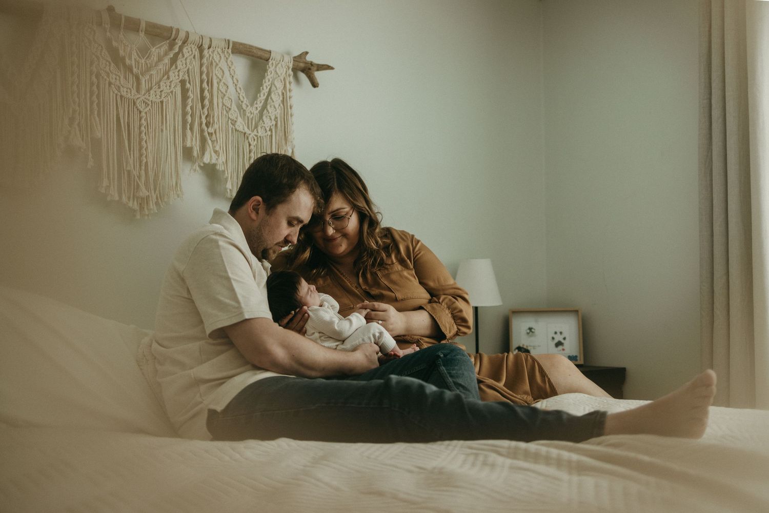 An intimate moment captured in a softly lit bedroom with natural window light.