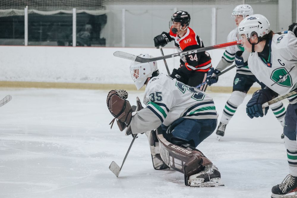 Hockey players battle for position near the goal during an intense game moment.