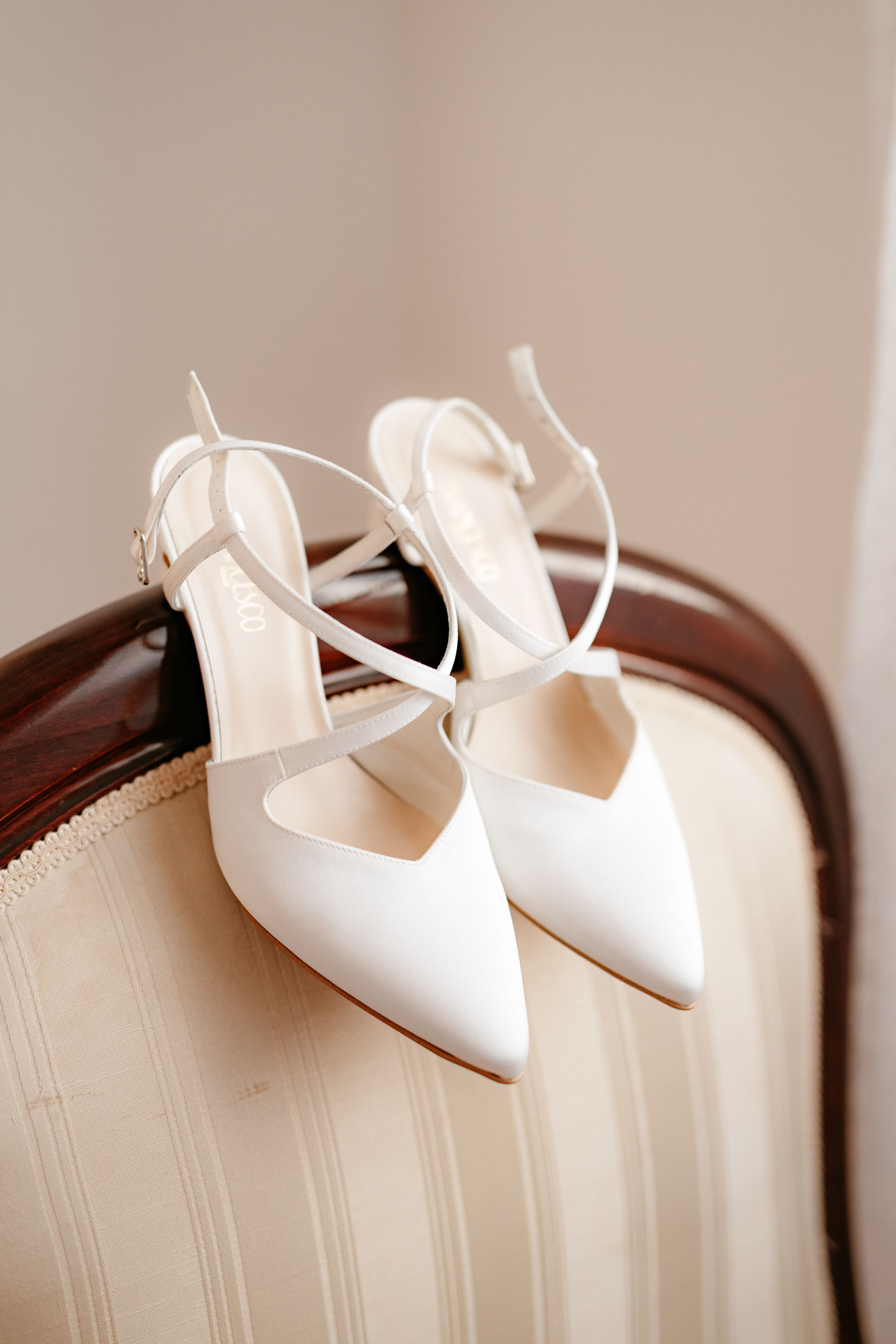 White ballet shoes are elegantly placed on top of an open book with cream-colored pages.
