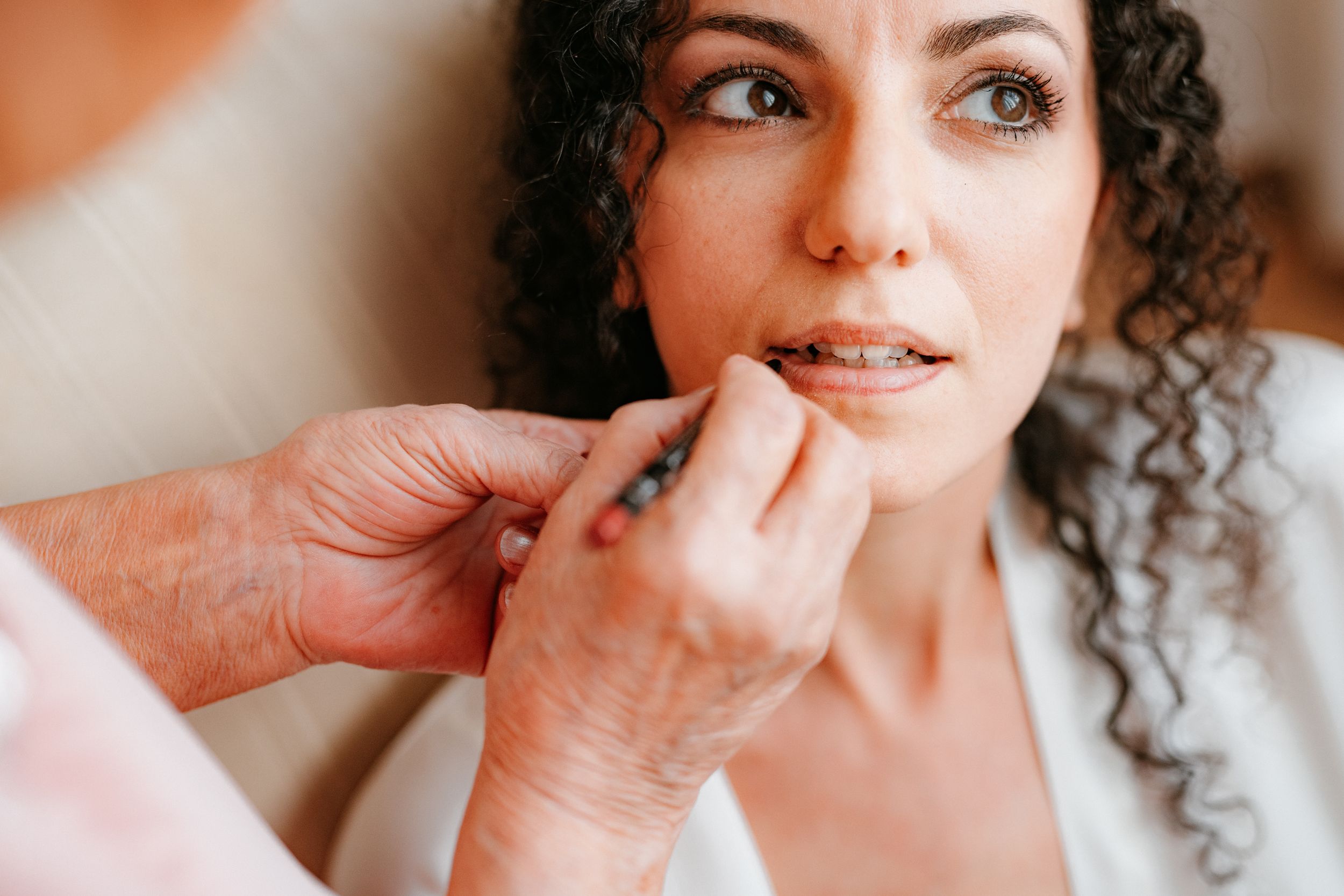 Makeup artist applies lipstick with a brush during professional beauty session.