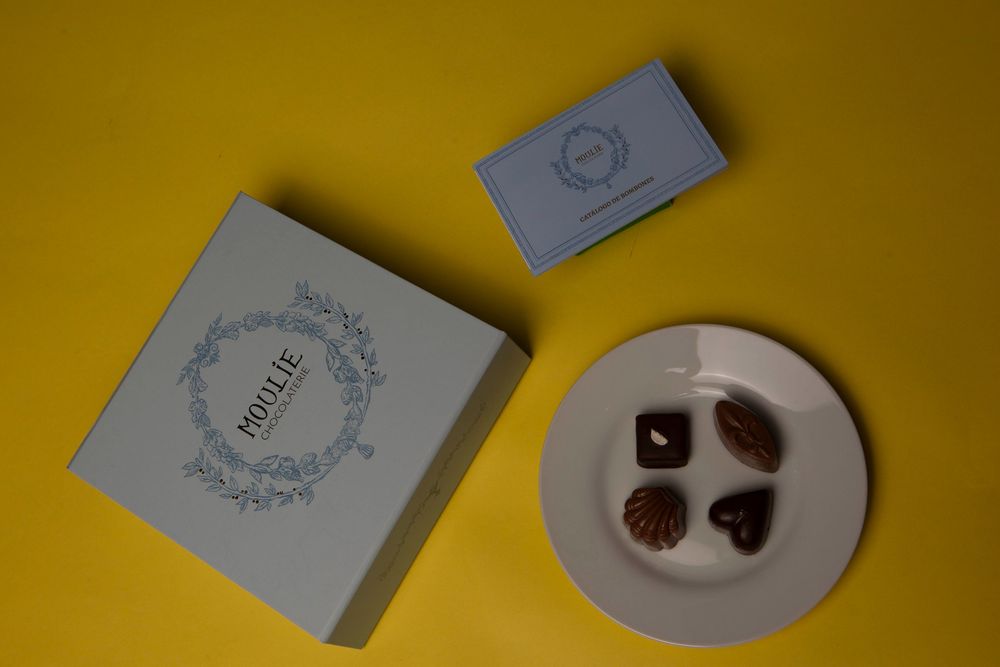 Trufas de chocolate artesanal en plato gris con fondo amarillo y borde de libro visible.