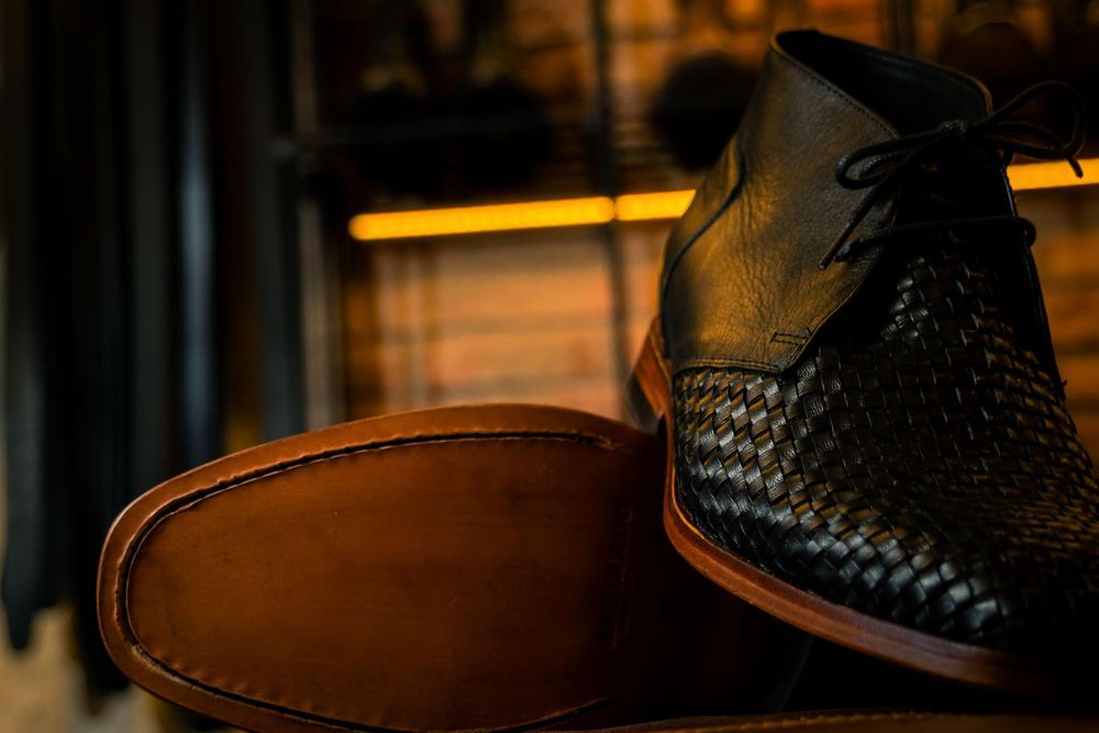 Detalle de zapato de cuero tejido con iluminación tenue y fondo cálido.