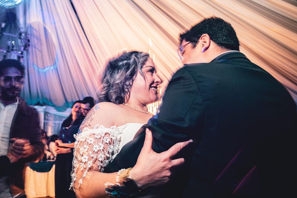 Pareja compartiendo un momento íntimo de baile bajo telas decorativas en la recepción de su matrimonio.