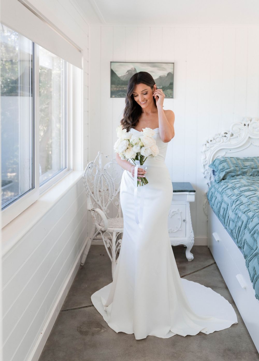 A sequence of elegant bridal portraits in a bright white room with a blue bed and large windows creating a dreamy atmosphere.