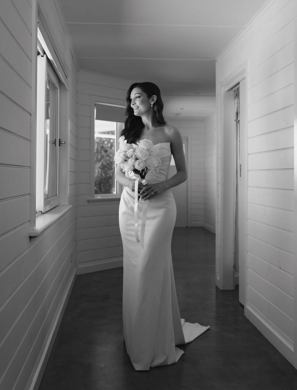 A series of black and white photos showing someone in a white dress walking through a minimalist hallway corridor.