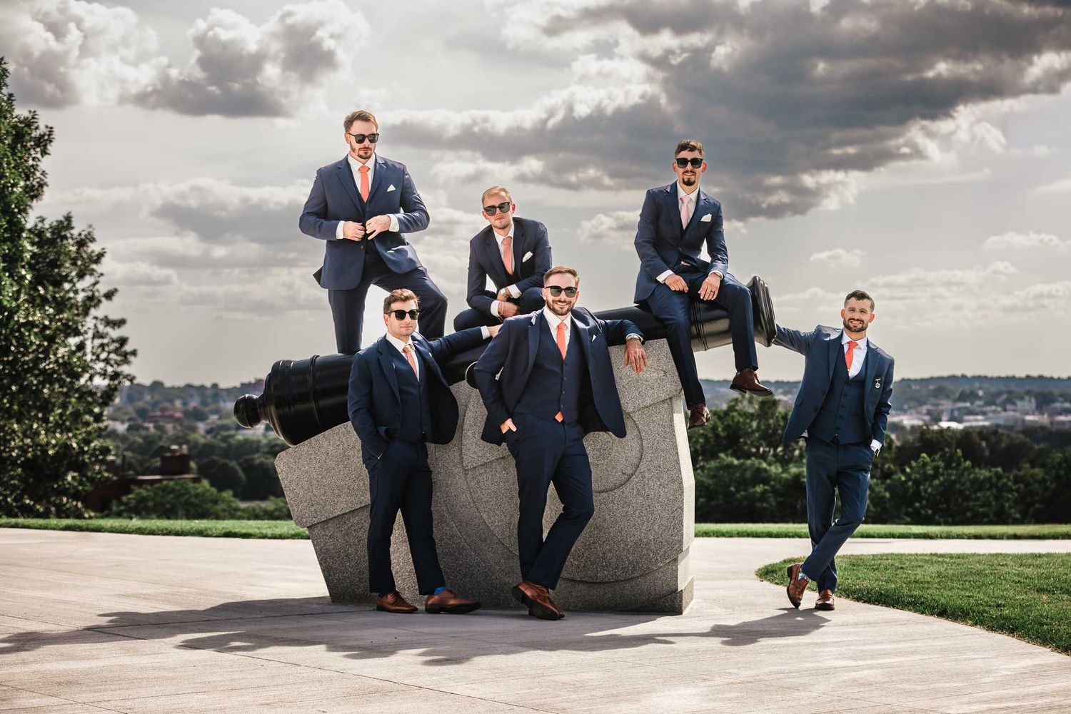 Groom and groomsmen posing on historic cannon at Dorchester Heights in South Boston during wedding portraits
