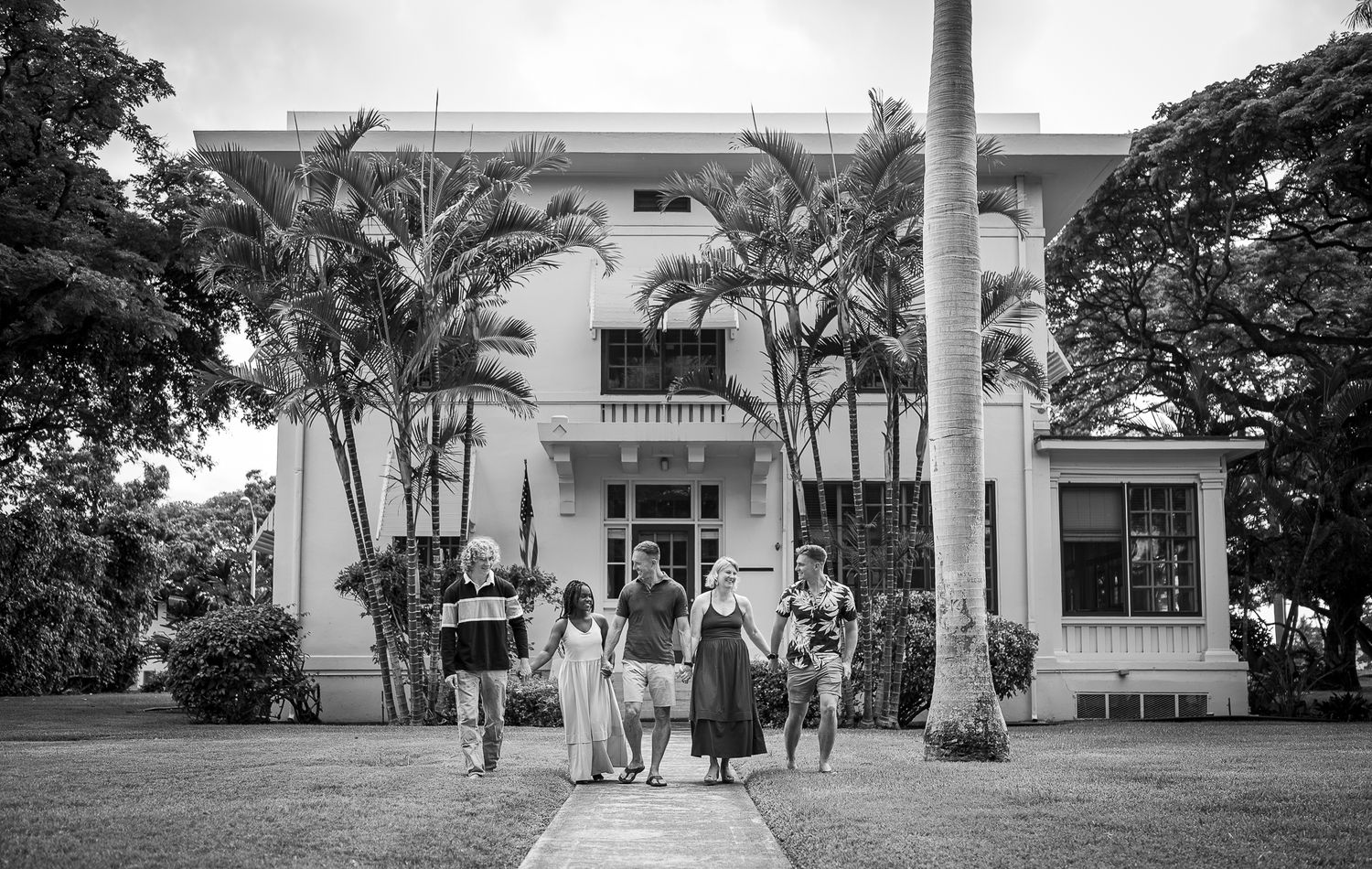 Black and white panoramic view of a historic plantation house with palm trees and columns.