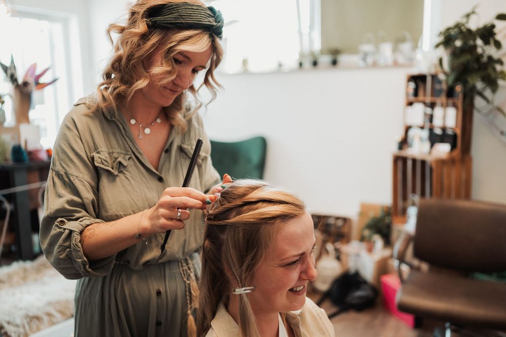 Hairstylist working with client in modern salon with natural lighting and professional equipment.