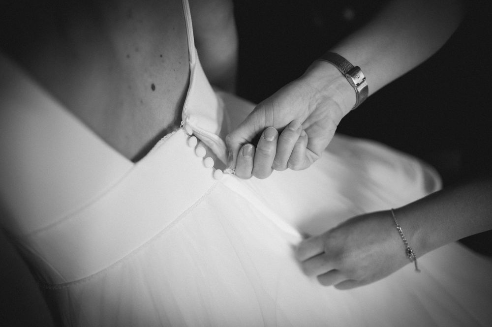 Black and white image showing hands carefully pinning fabric on a dress form during garment construction.
