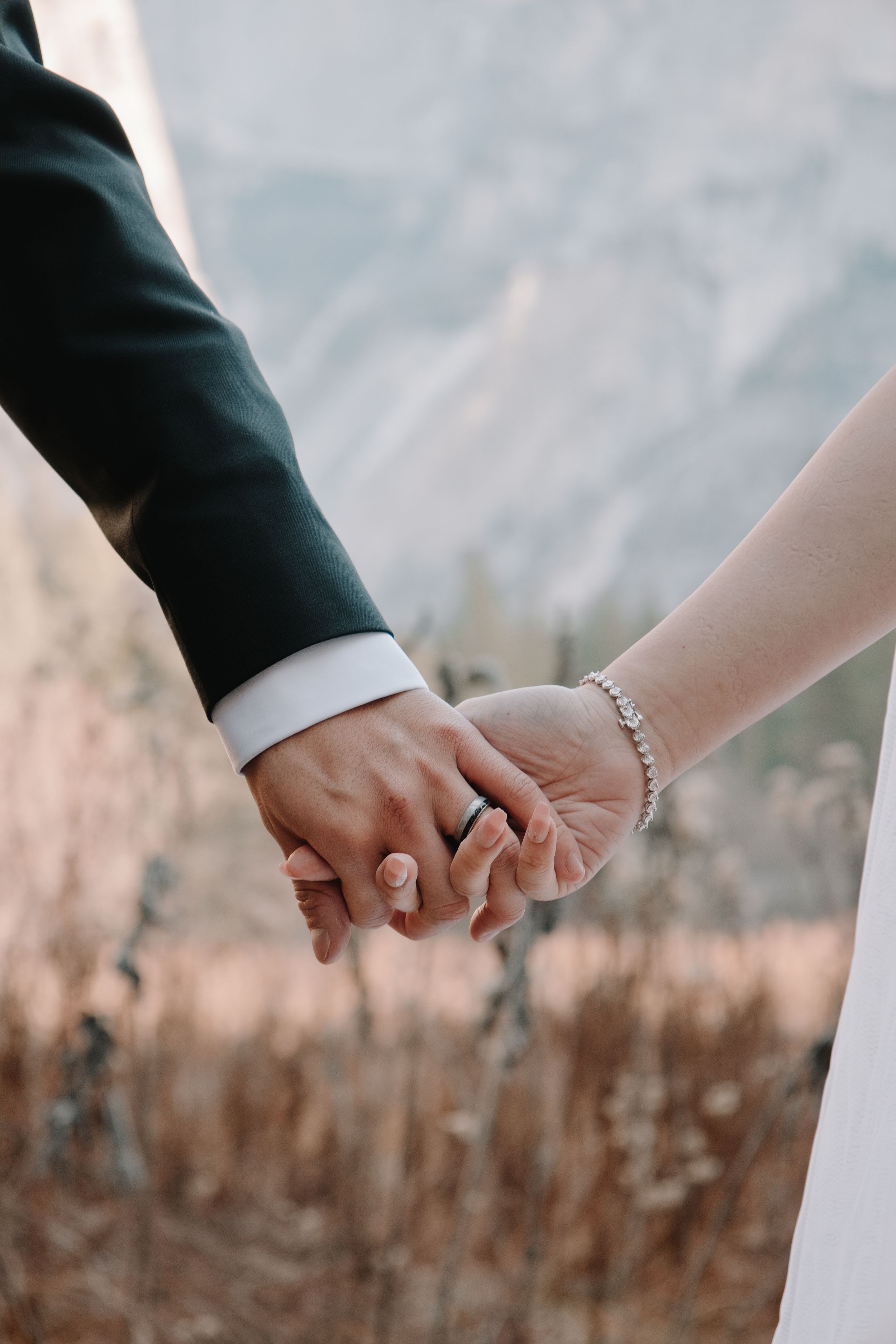 A series of close-up shots showing two hands holding each other against a blurred natural outdoor background in Yosemite valley.