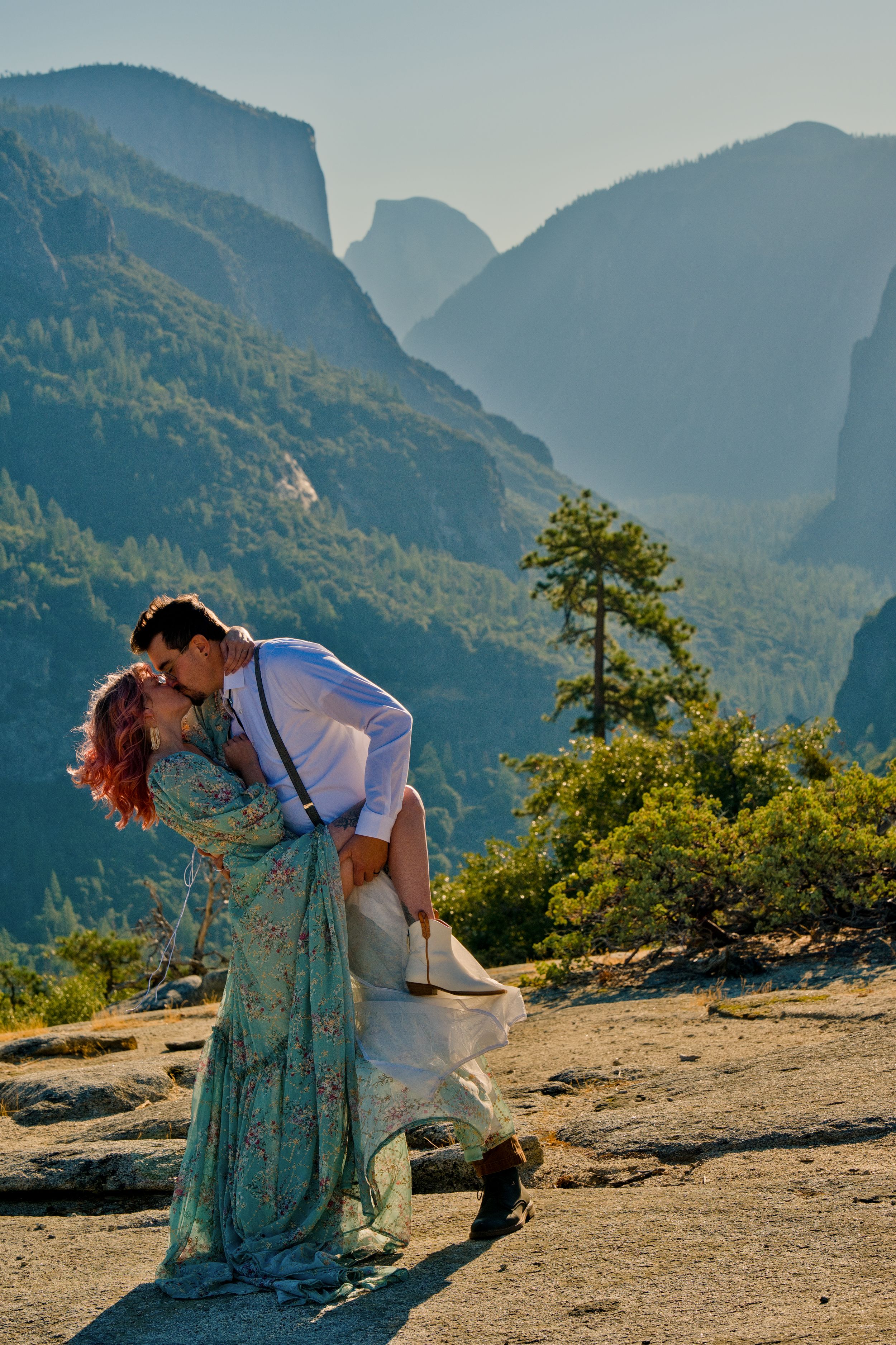 A romantic elopement couple dips against a stunning mountain backdrop in Yosemite Valley during golden hour. Half dome in the background.