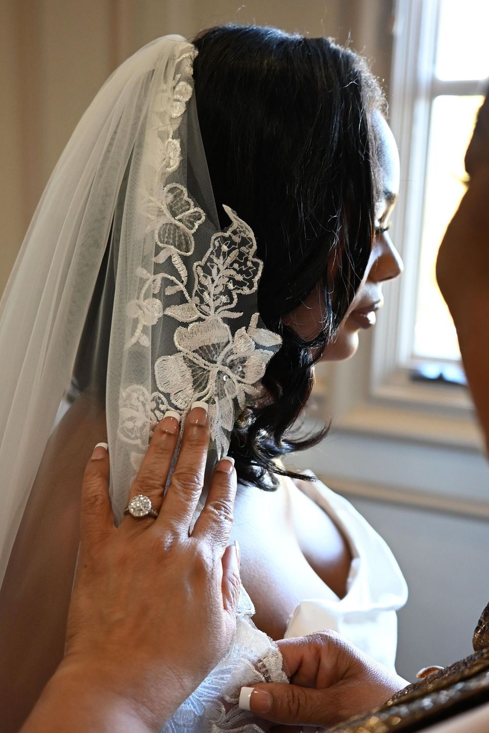 Side profile of a bride wearing a delicate lace veil during wedding preparations.