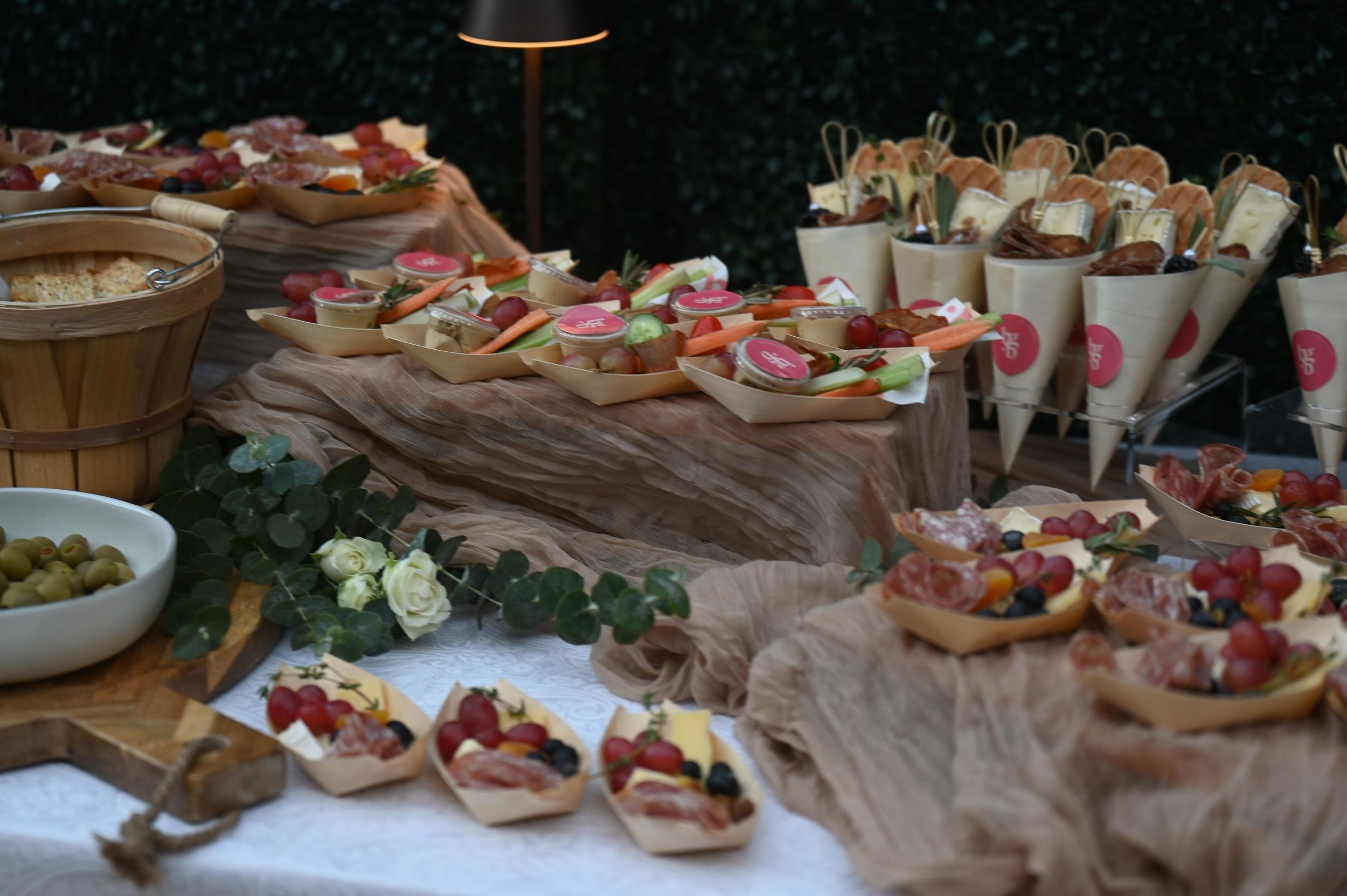 Elegant catering display featuring appetizers and hors d'oeuvres arranged on rustic brown paper with decorative flowers.