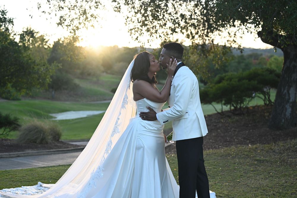 A couple embraces during their wedding photoshoot on a scenic golf course at golden hour.