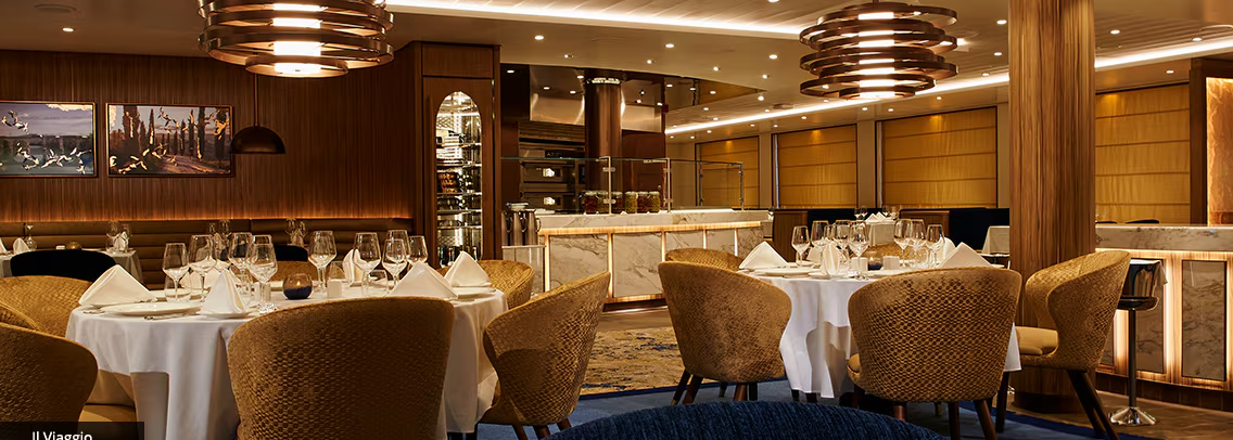Interior view of an upscale restaurant dining room with warm lighting, wooden tables, and modern decor.