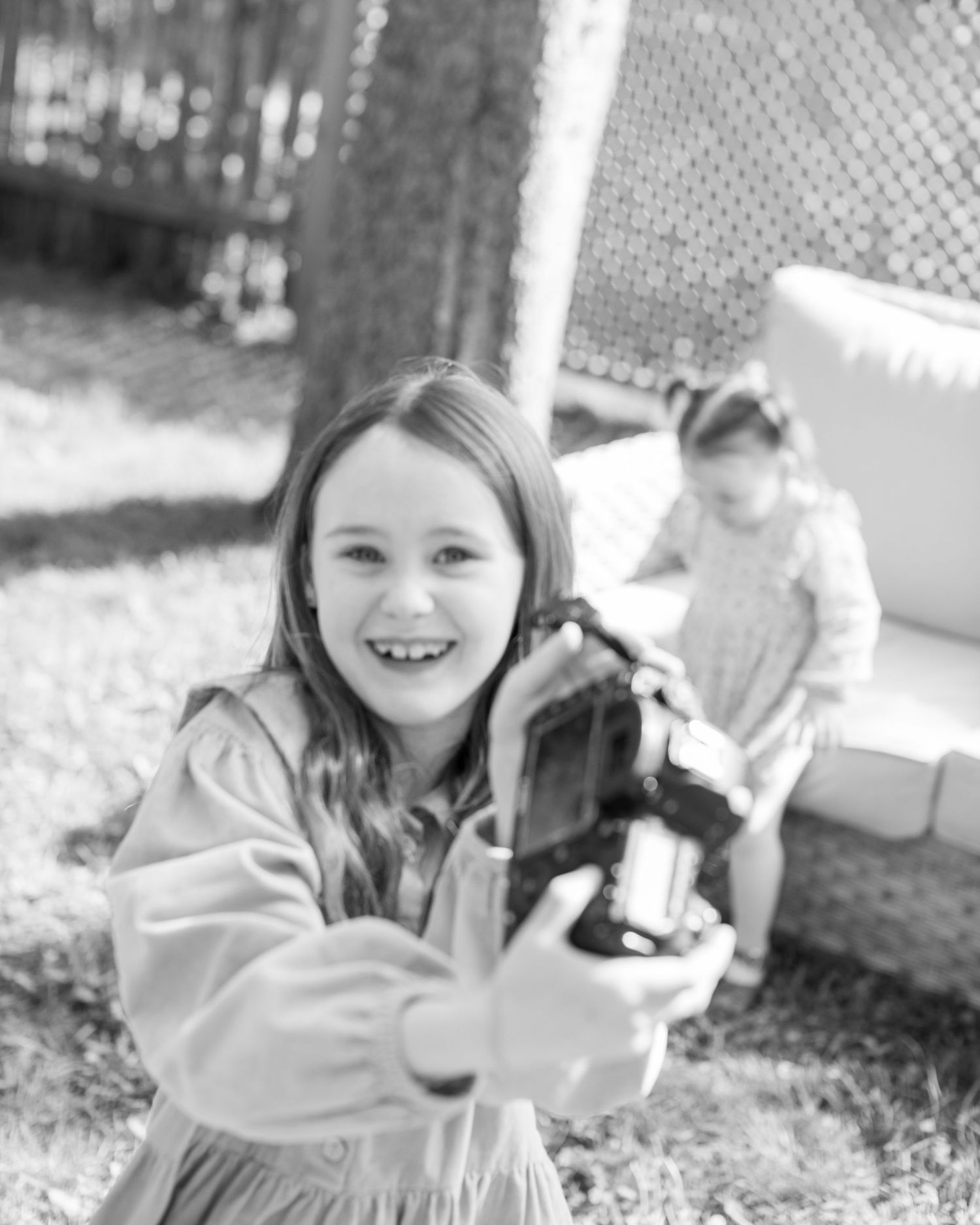 A sequence of black and white photos shows a child playing and laughing outdoors in a casual setting.