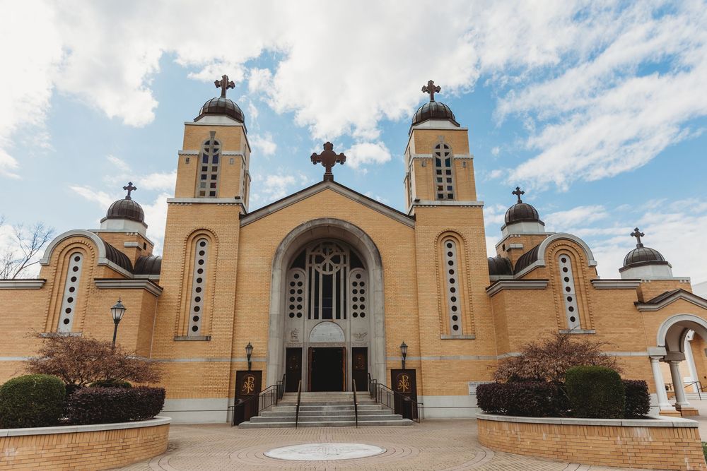 A row of identical yellow and white Greek Orthodox church buildings with crosses and domed towers against a blue sky.