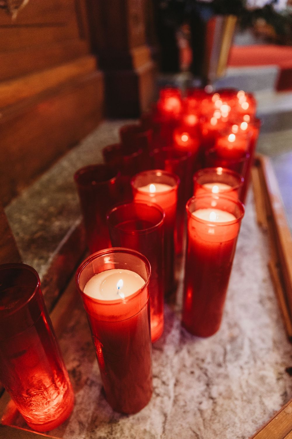 Red votive candles glowing in glass jars create a warm, spiritual atmosphere.