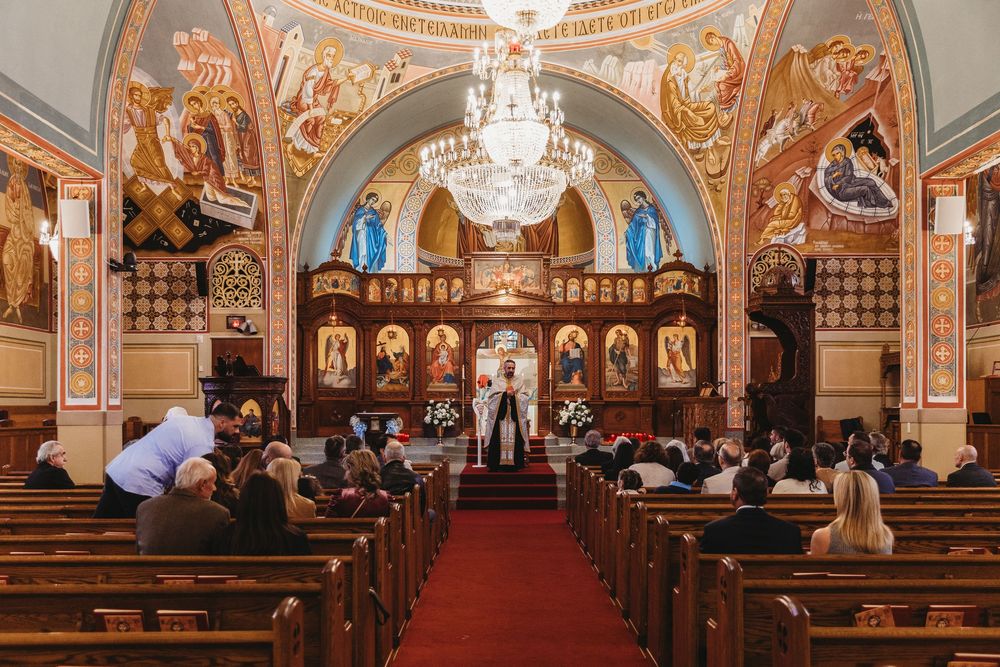 Interior panorama of an ornate Orthodox church with chandelier and detailed iconography.