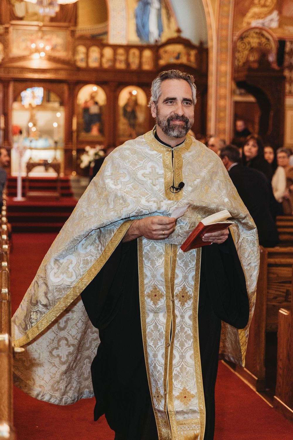 Clergy members in ornate white and gold vestments conducting a religious ceremony.