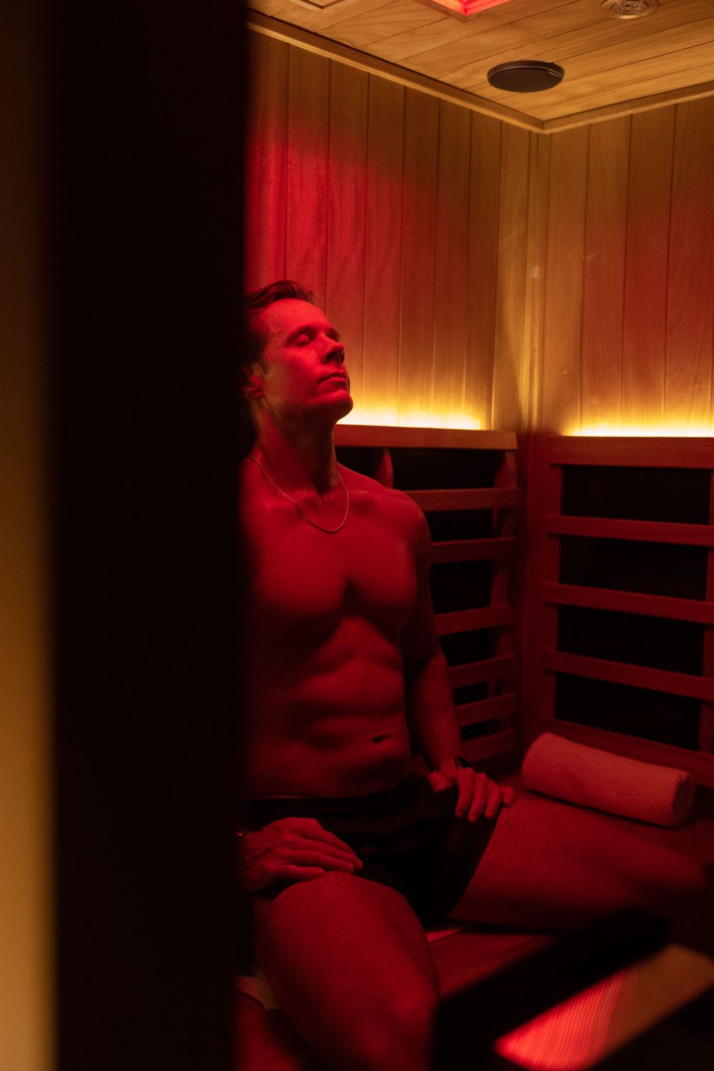 Interior of a sauna room with wooden panels and red ambient lighting.