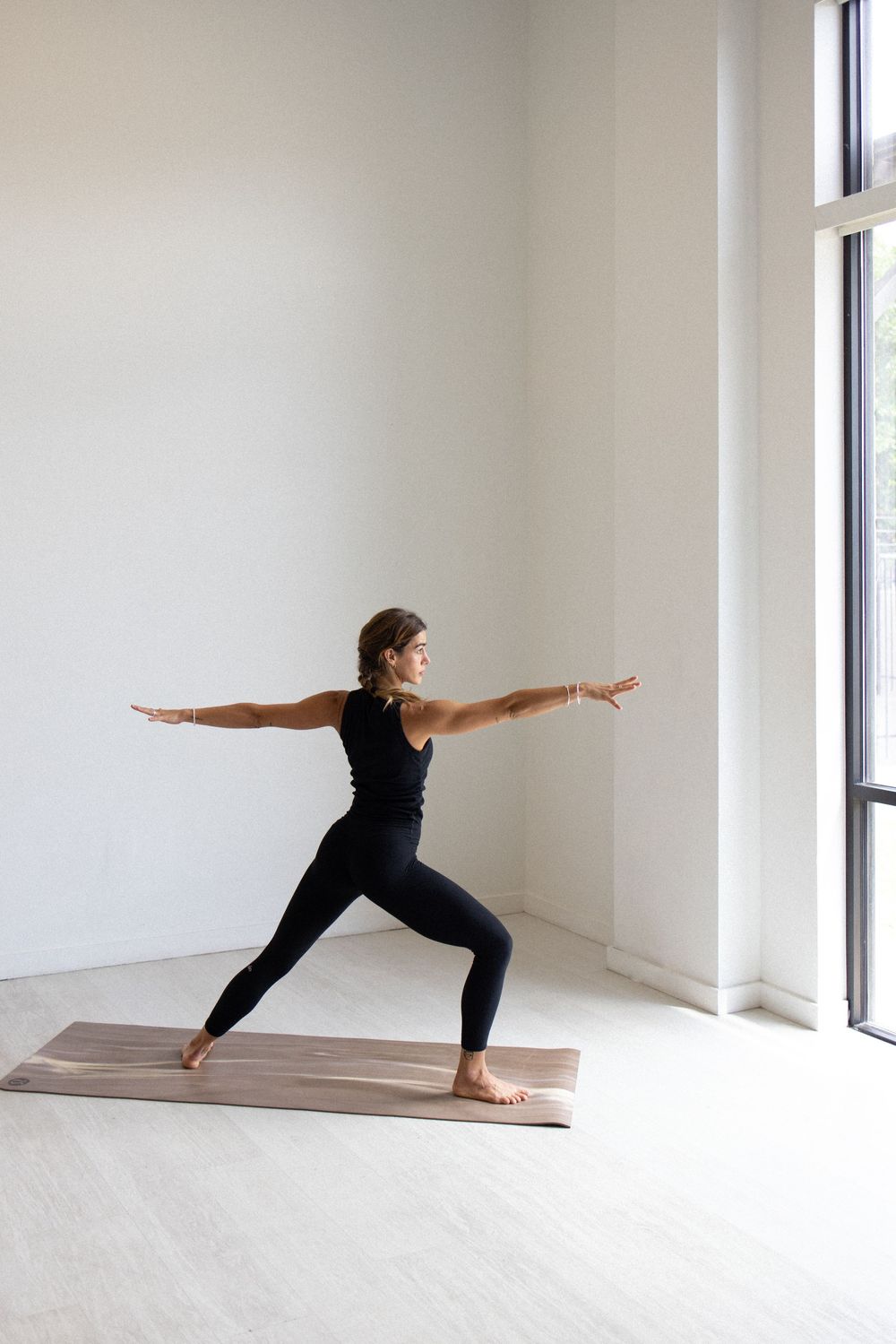Yoga poses demonstrated in a bright, minimalist white studio space with large windows.